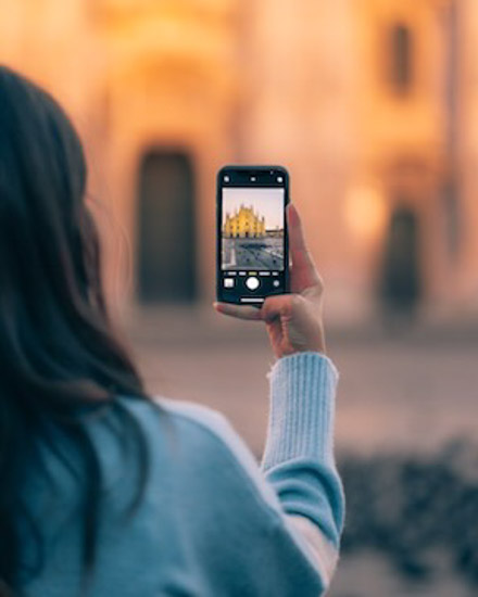 Tourist woman taking cell phone photo of iconic cathedral